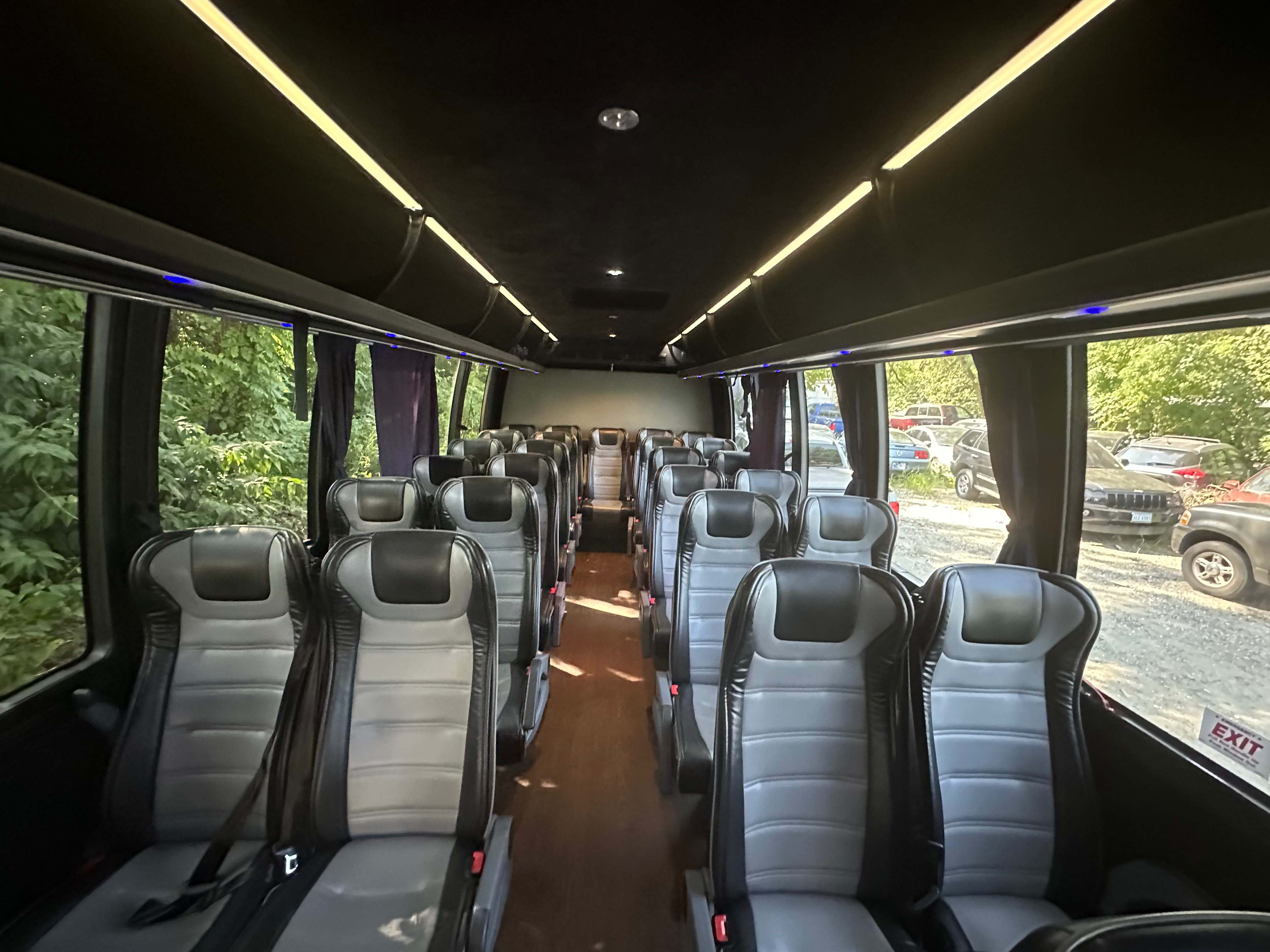Mini coach bus interior aisle with tiered leather seating and ambient LED ceiling lighting