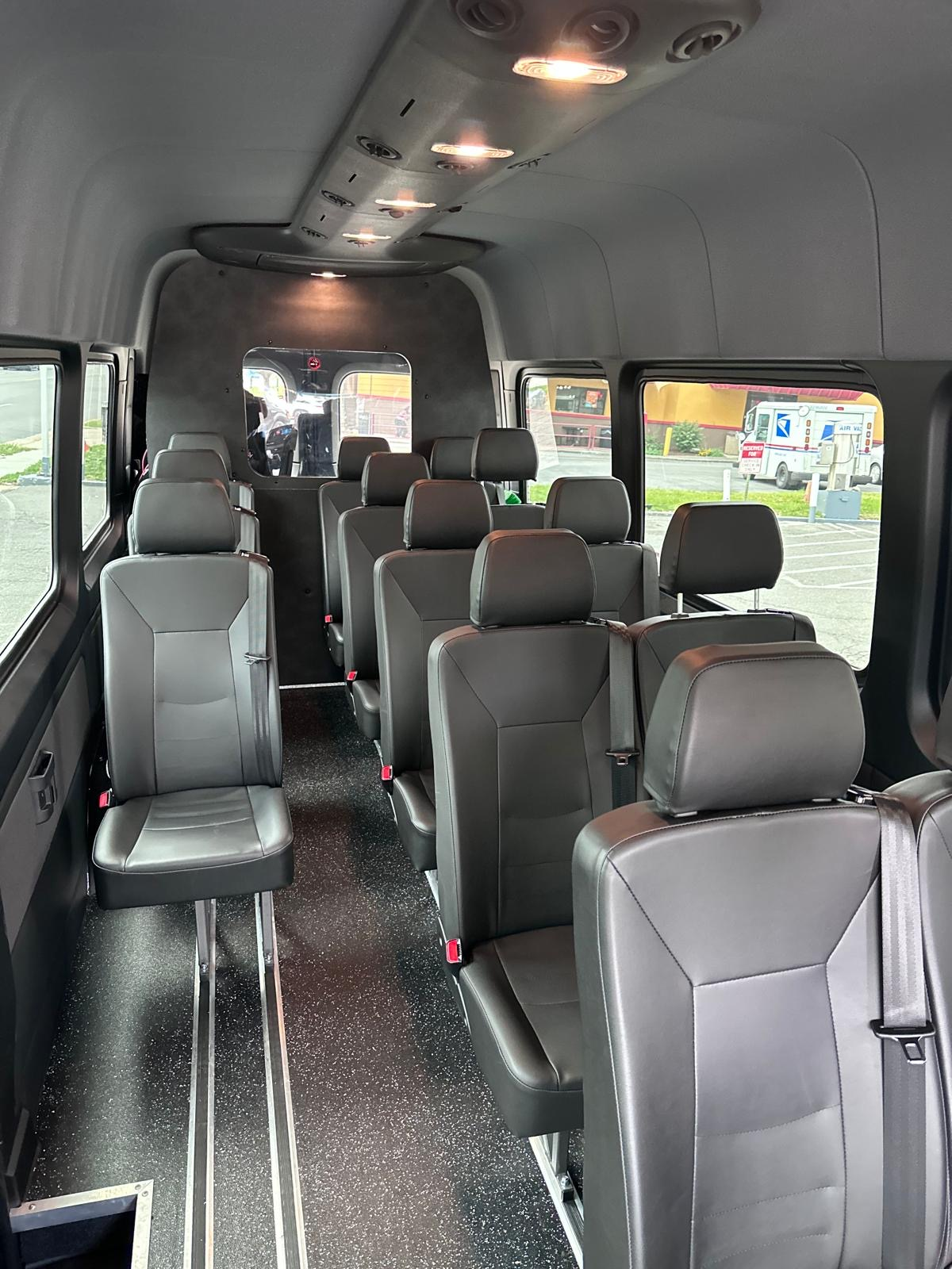 Mini coach bus interior with rows of black leather passenger seats