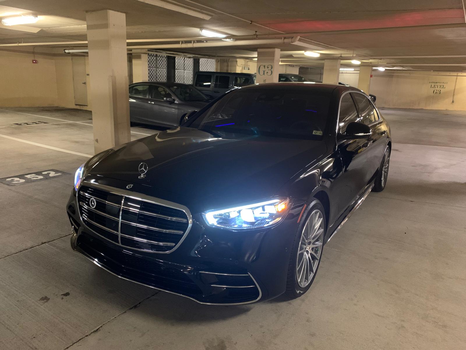 Black Mercedes-Benz S-Class parked in a garage, front view with headlights on